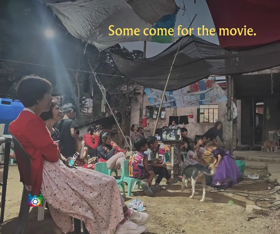 Some come for the movie — a wide crowd gathered under a tarp shelter to watch