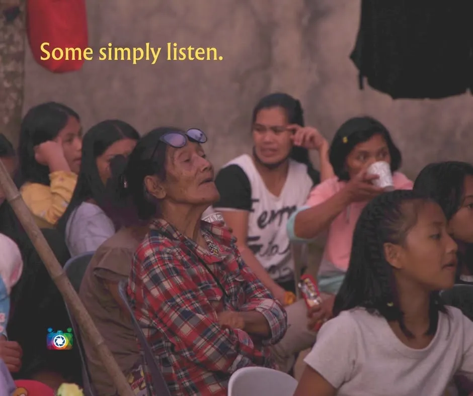 Some simply listen — an older woman in the crowd listening intently